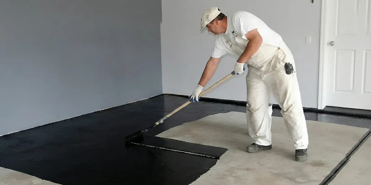 basement waterproofing professional applying waterproof coating to protect a basement floor in Overland Park, KS